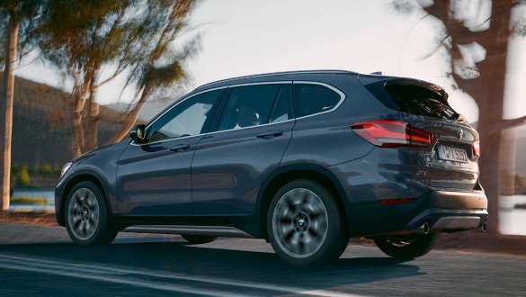 BMW X1, three-quarter rear view. BMW X1, three-quarter rear view driving in front of mountain scenery.