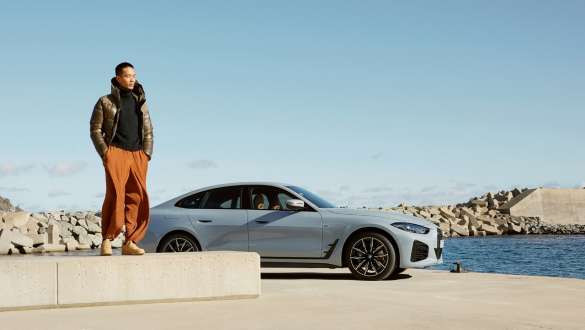 BMW Service Inclusive man in front of BMW i4 (G26) on the coast BMW Service Inclusive man in front of BMW i4 (G26) on the coast