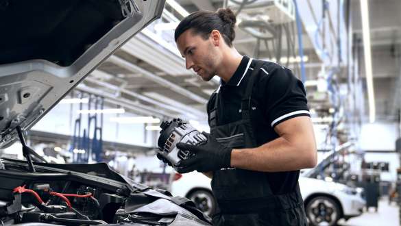 BMW Value Service Value Repair service offers BMW Value Service workshop employee holds an alternator